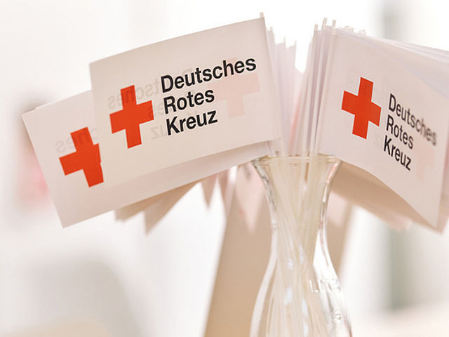 viele kleine DRK Fahnen in einem Glas stehend