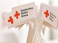 viele kleine DRK Fahnen in einem Glas stehend