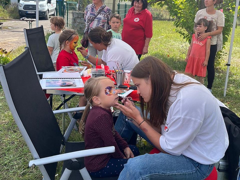 Jugendliche schminken mehrer Kinder im Gesicht