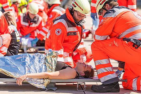 Zwei Sanitäter hocken über einer Person auf einer Trage