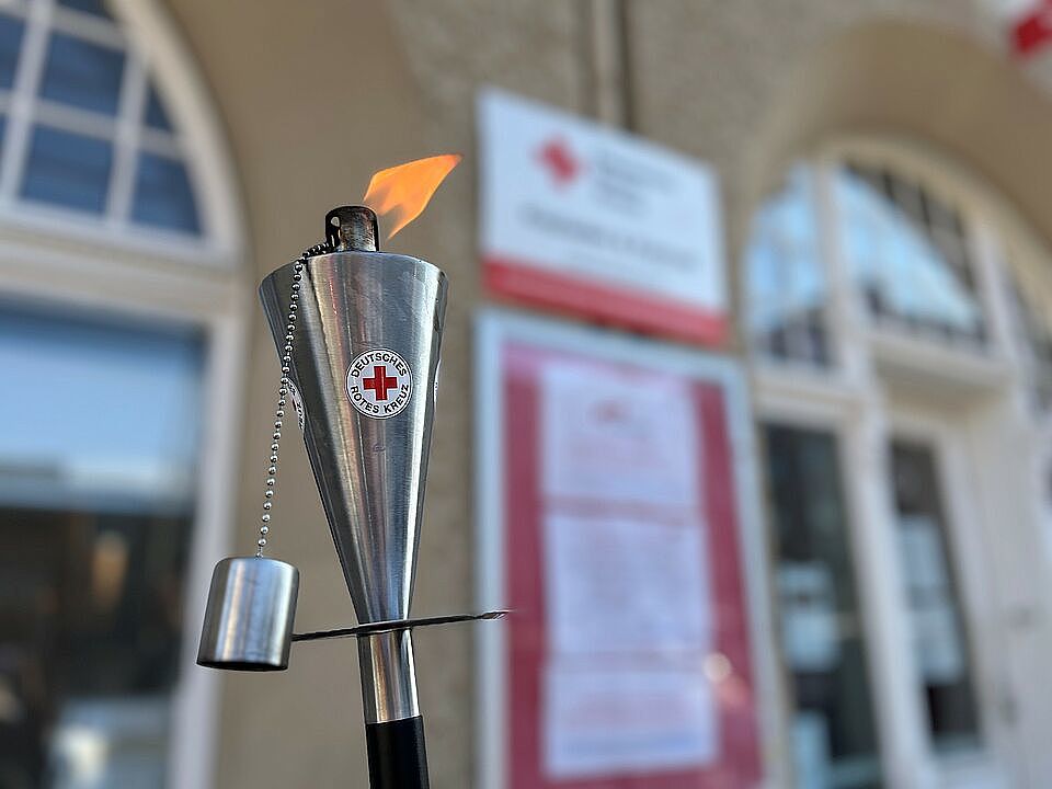 Eine brennende Metallfackel mit einem Roten Kreuz