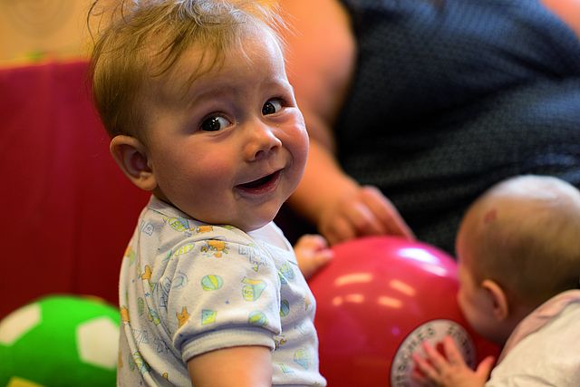 Baby schaut lächelnd in Kamera