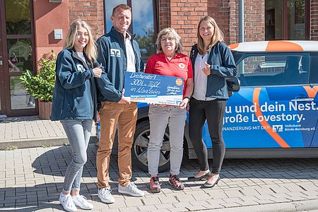 vier Personen halten symbolischen Check