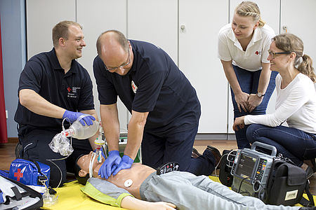 ZWei Sanitäter hocken über einem Übungstorso und führen eine Herzdruckmassage aus