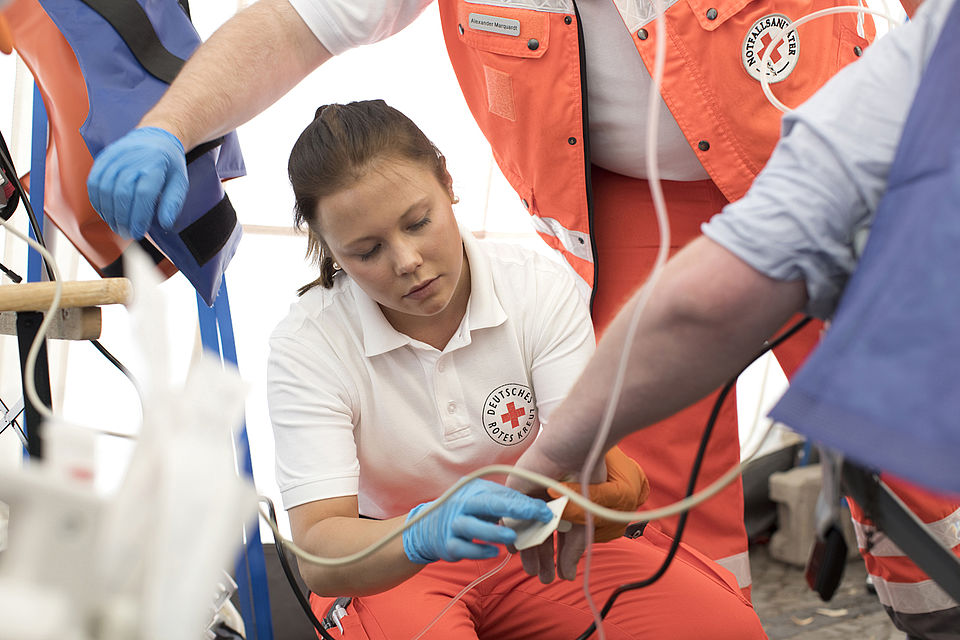 Sanitäterin legt einen Zugang bei einem Patienten