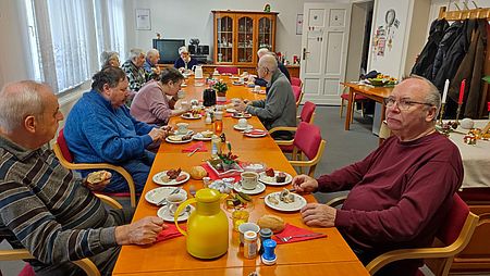 Senioren sitzen an Tafel mit Frühstück