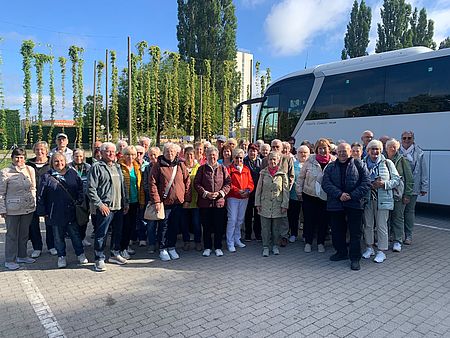 Eine große Reisegruppe steht vor einem Bus