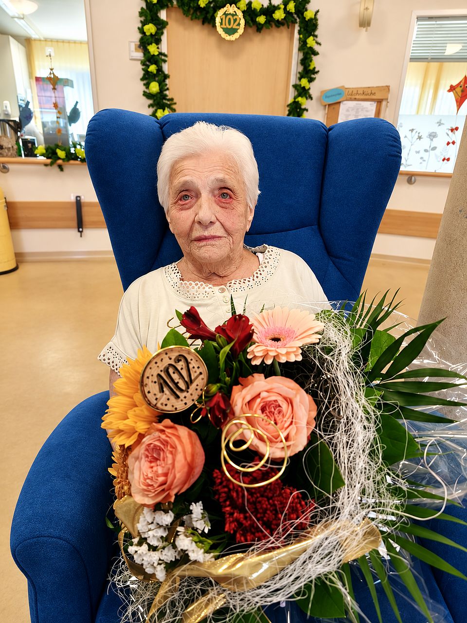 Ursula Spalke feiert ihren 102. Geburtstag Eine alte Frau sitzt in einem Sessel und hällt einen großen Blumenstrauß