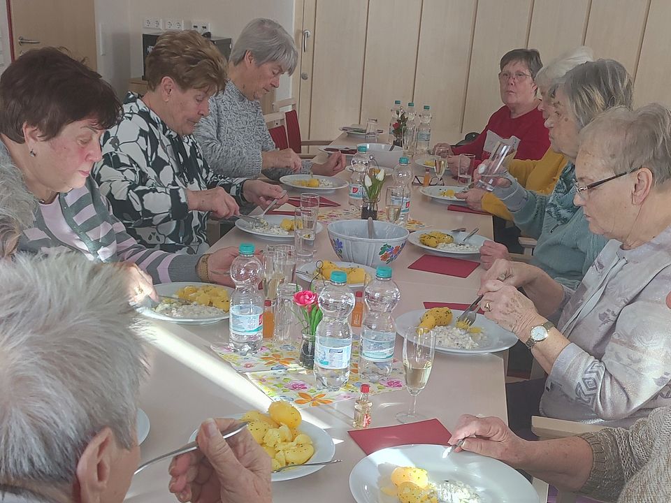 mehrere Semiorinnen sitzen an einer Tafel und Essen Heringssalat mit Kartoffeln
