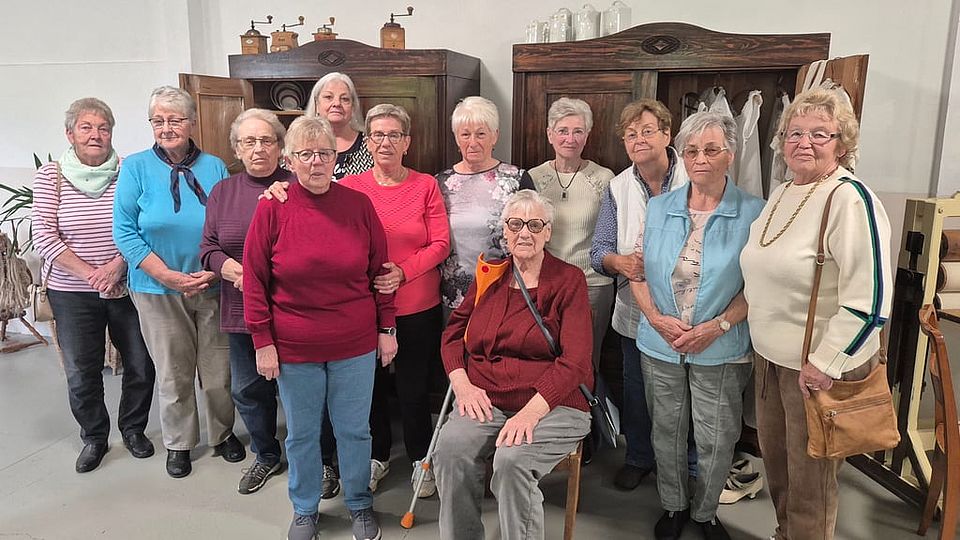 mehrere Seniorinnen stehen vor alten Kleiderschränken