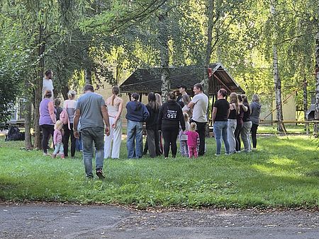 Teilnehmer versammelt um Vortragenden in wäldlicher Umgebung