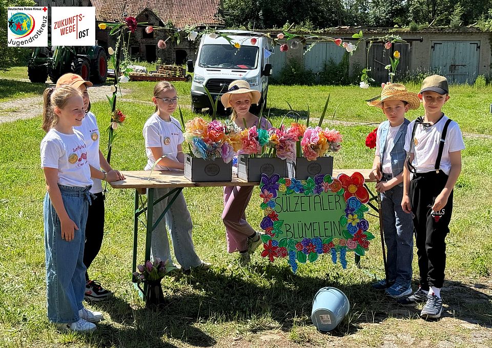 4 Kinder stehen an einem Tisch mit Blumen
