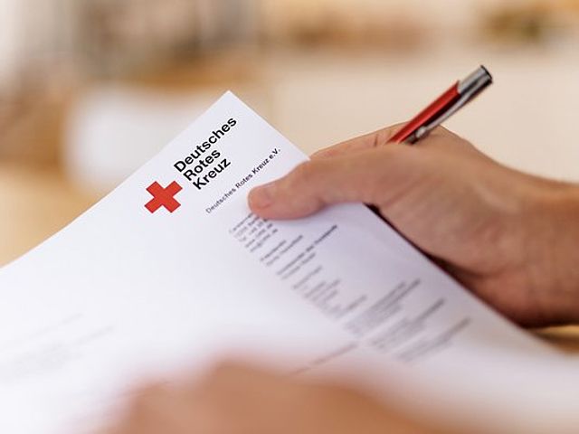 DRK Kopfbogenpapier in der Hand haltend