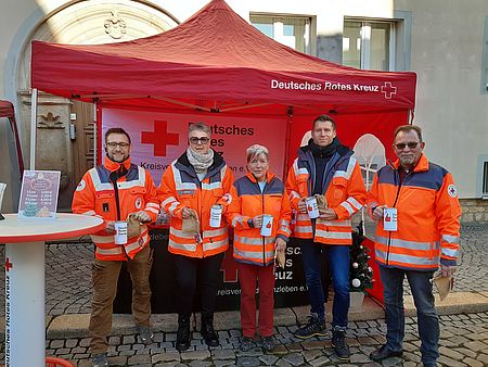 Helfer des DRK Kreisverbands Wanzleben waren ausgestattet mit Spendendosen und Losen. Gemeinsam sammelten sie für einen guten Zweck. Fünf Personen in DRK Kleidung und mit Sammelödosen stehen vor einem DRK-Pavillon
