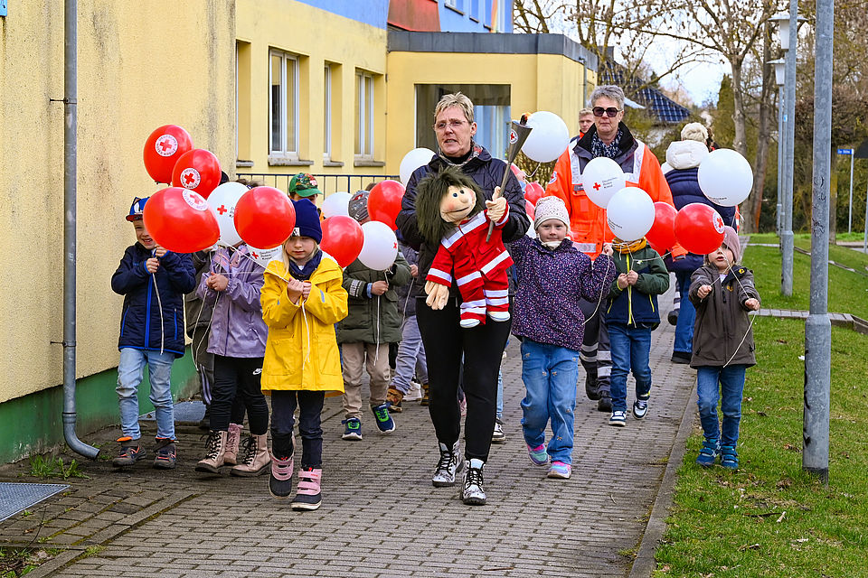 Kinder mit Luftballons tragen eine Fackel