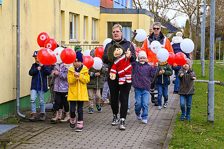 Kinder mit Luftballons tragen eine Fackel