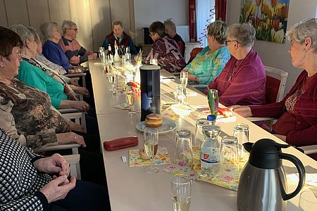 mehrere Senioren sitzen an einer Tafel mit Sektgläsern