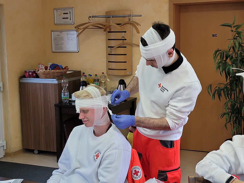 Bei den Übungen zur Sanitätsdienstausbildung muss jeder Handgriff sitzen. Zwei Sanitäter in Ausbildung verbinden sich gegenseitig am Kopf