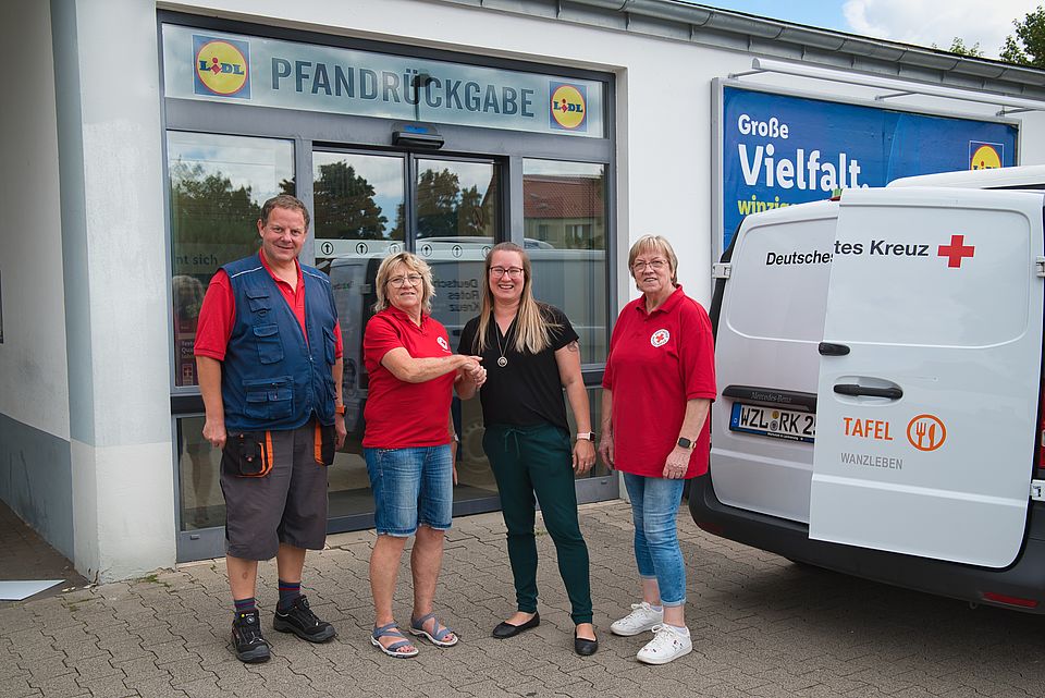 Die Tafeln in Wanzleben erhalten eine Spende aus Pfandeinnahmen durch Lidl Drei Frauen und ein Mann stehen vor der Lidl-Pfandstation und reichen sich die Hände