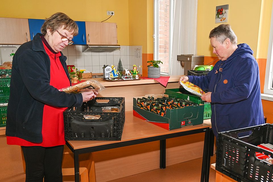 Zwei Mitarbeiterinnen sortieren Kisten mit gespendeten Lebensmitteln